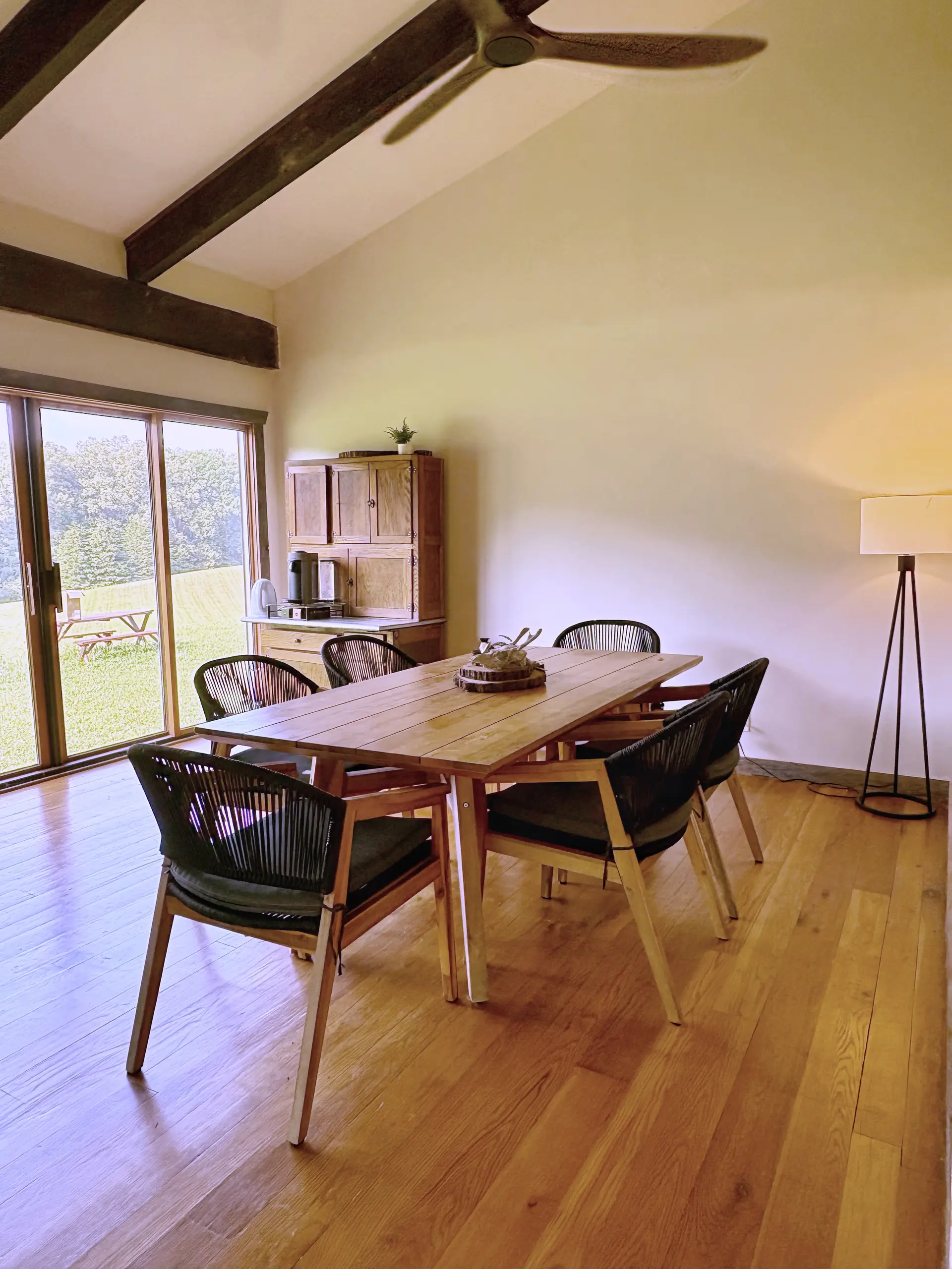 A long table and chairs in the barn apartment, sliding doors open onto the field beyond