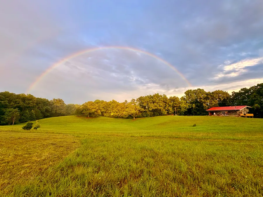 A rainbow arcing over the barn and the open field below it