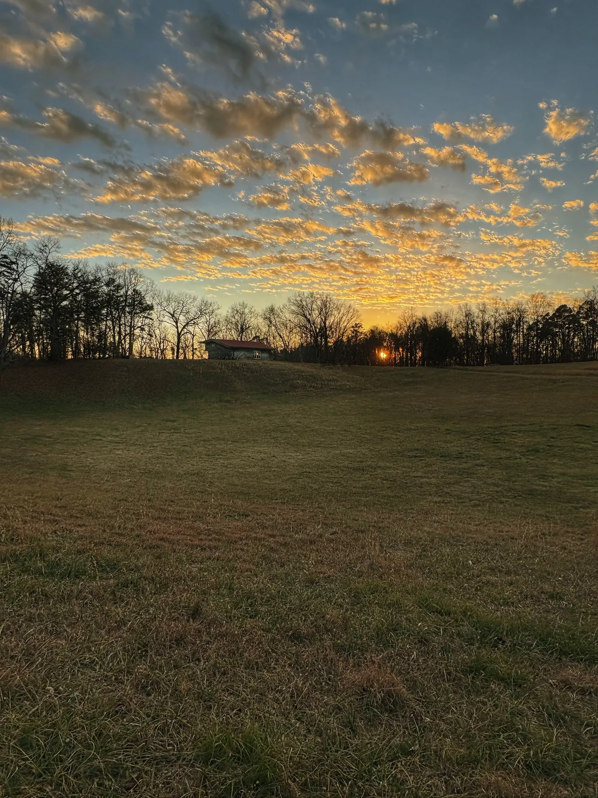 The barn seen from across a wide open field at sunset