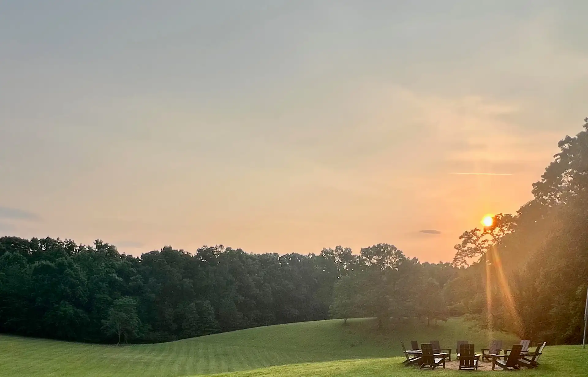 Chairs drawn into a circle around the fire pit as the sun drops behind the trees